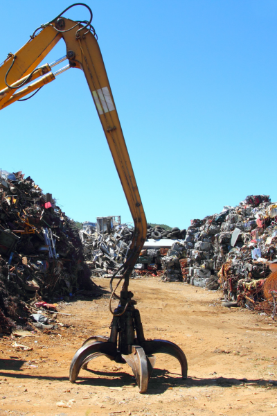 claw attachment on the ground in the foreground and junk yard behind